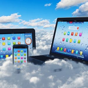 Creative cloud computing concept: modern laptop notebook, tablet computer PC and black glossy touchscreen smartphone in the blue sky with clouds